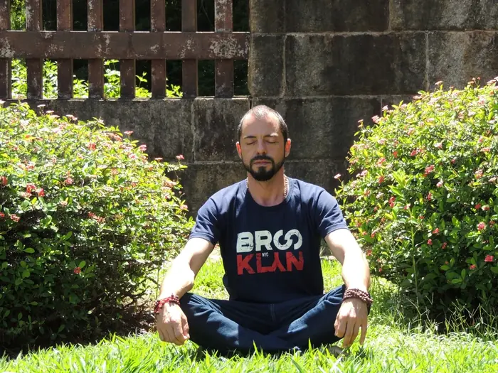 Postura de meditação no jardim, mãos abertas sobre os joelhos