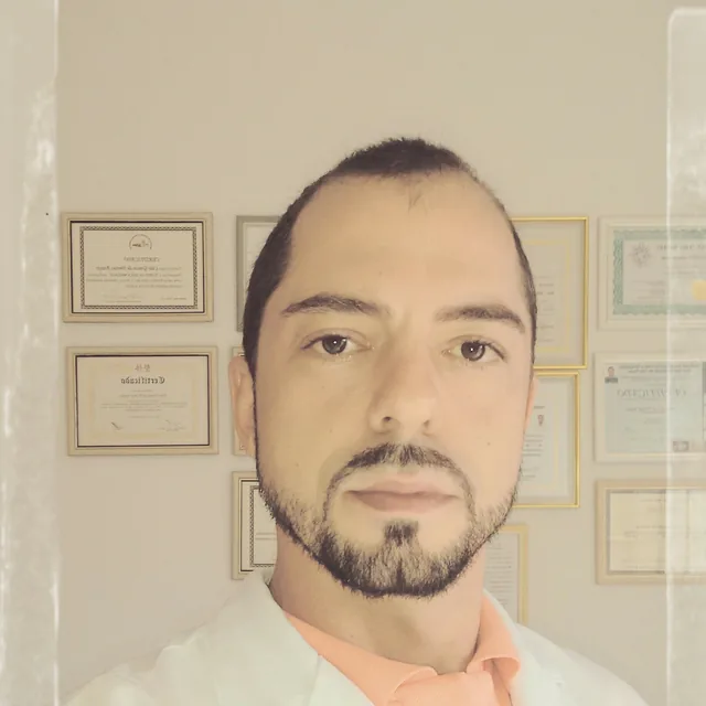 Caio Gracco em seu consultório, Retrato profissional, com os certificados de formação ao fundo
